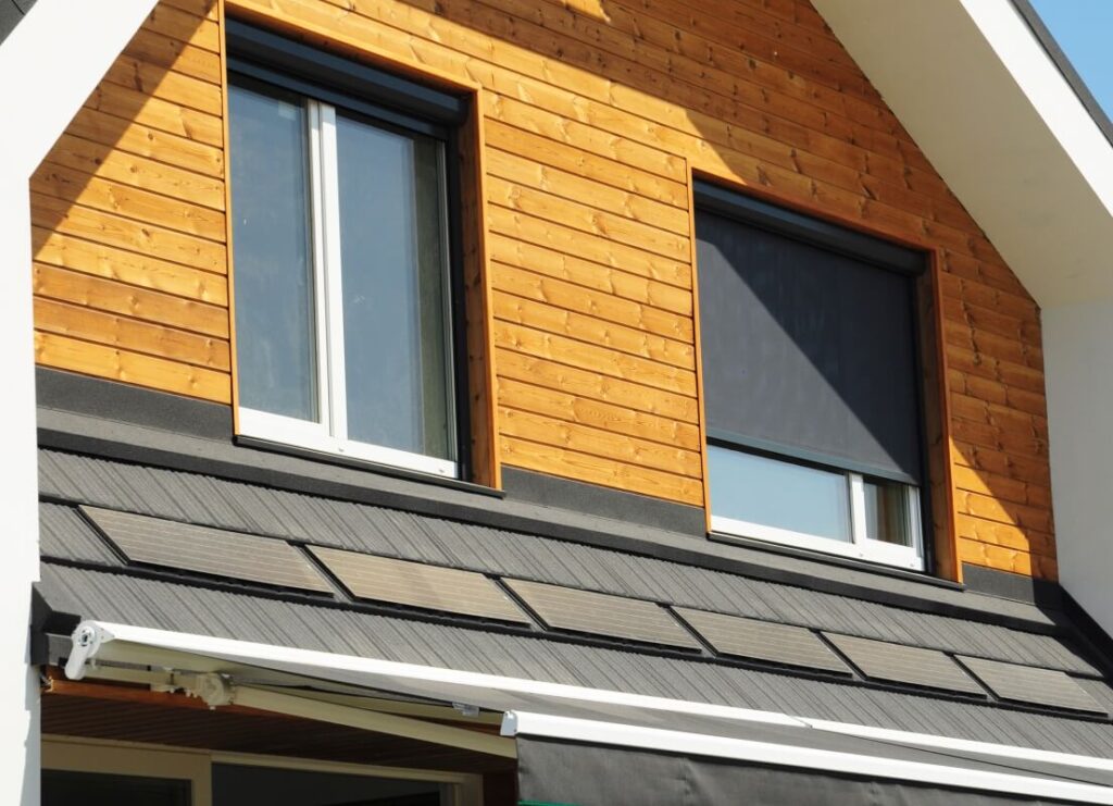 Drewniany dom z wyciągniętą markizą nad oknami.